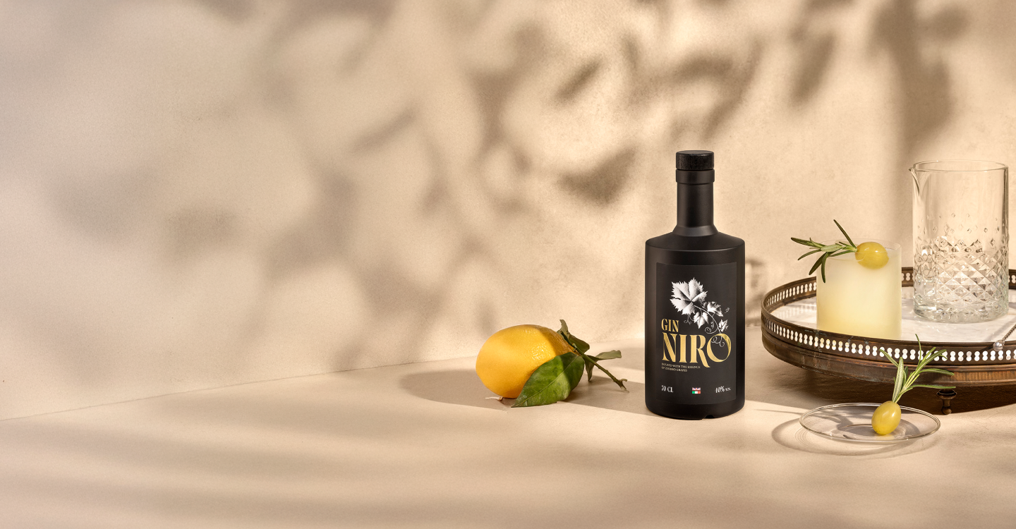 Cocktail Niro Smash giallo con rosmarino e limoni freschi accanto alla bottiglia GIN NIRO
