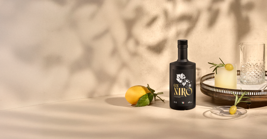 Cocktail Niro Smash giallo con rosmarino e limoni freschi accanto alla bottiglia GIN NIRO